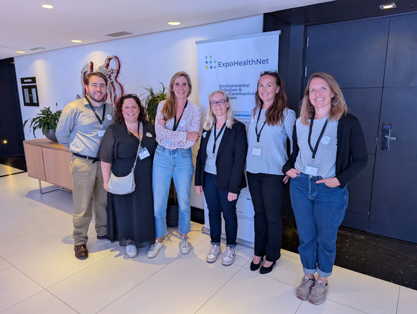 Six people standing in front of a banner stand titled ExpoHealthNet